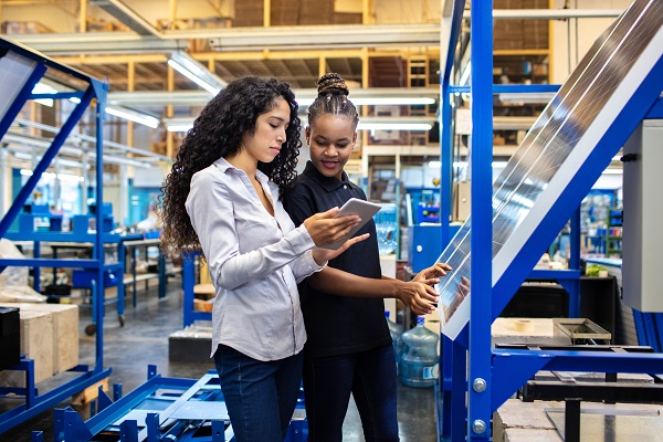 Female engineer showing the production plan to a worker on her digital tablet.